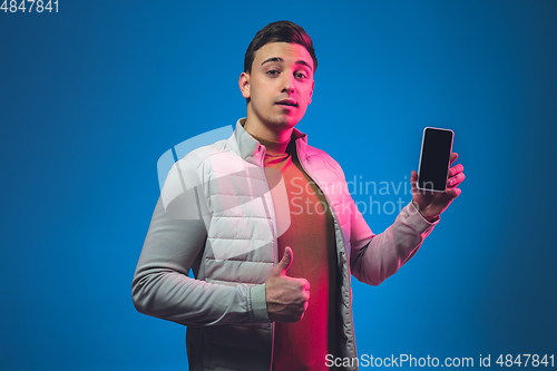 Image of Caucasian man\'s portrait isolated on blue studio background in neon light
