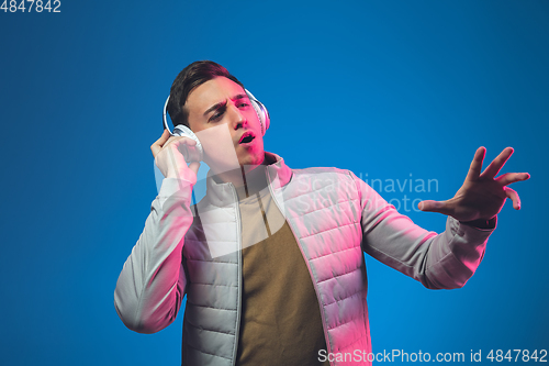 Image of Caucasian man\'s portrait isolated on blue studio background in neon light