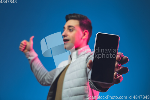 Image of Caucasian man\'s portrait isolated on blue studio background in neon light