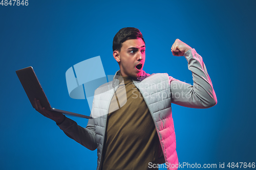 Image of Caucasian man\'s portrait isolated on blue studio background in neon light