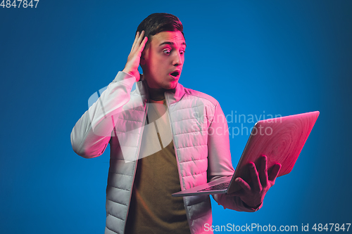 Image of Caucasian man\'s portrait isolated on blue studio background in neon light