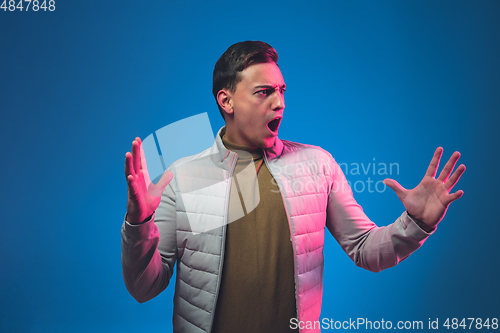 Image of Caucasian man\'s portrait isolated on blue studio background in neon light