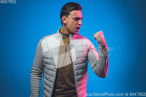 Image of Caucasian man\'s portrait isolated on blue studio background in neon light
