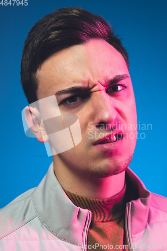 Image of Close up caucasian man\'s portrait isolated on blue studio background in neon light