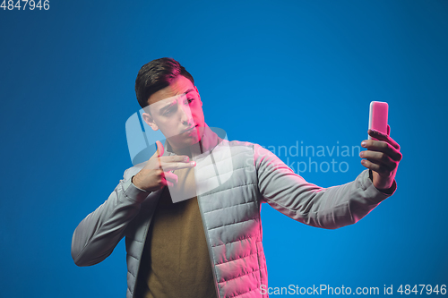 Image of Caucasian man\'s portrait isolated on blue studio background in neon light