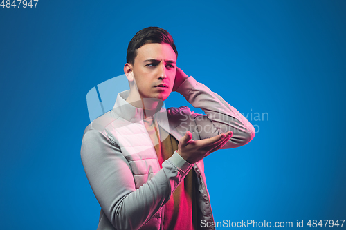 Image of Caucasian man\'s portrait isolated on blue studio background in neon light