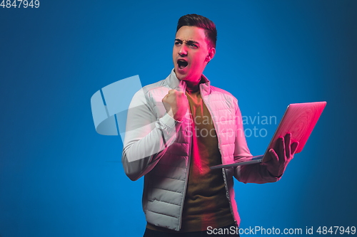 Image of Caucasian man\'s portrait isolated on blue studio background in neon light