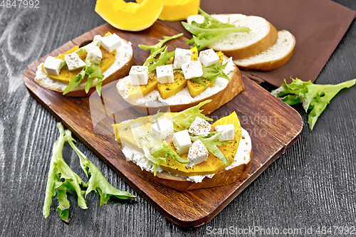 Image of Bruschetta with pumpkin and arugula on dark board