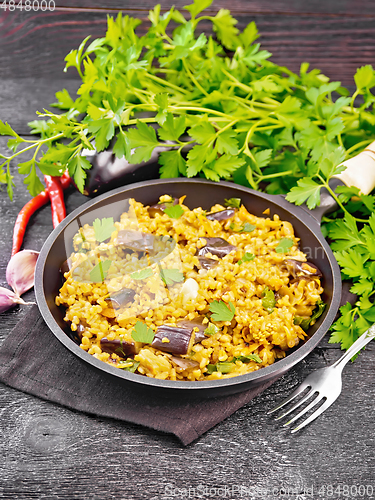 Image of Bulgur with eggplant in pan on wooden board