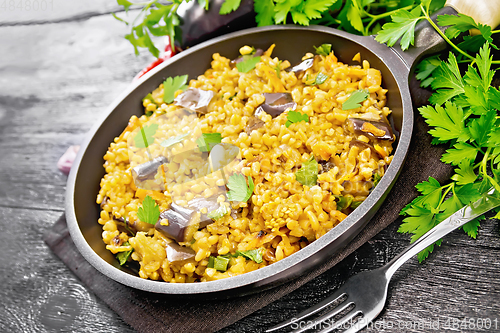 Image of Bulgur with eggplant in pan on wooden table