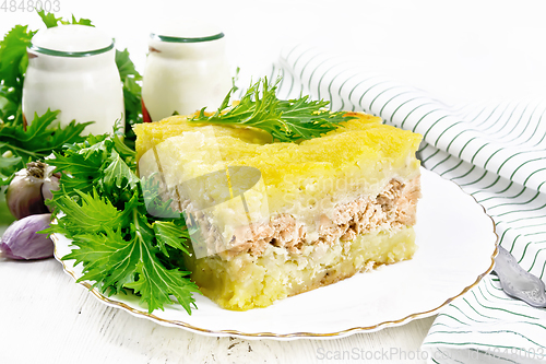 Image of Casserole with potatoes and fish in plate on light board