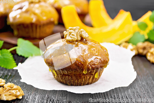 Image of Cupcake pumpkin with orange glaze and walnuts on dark board