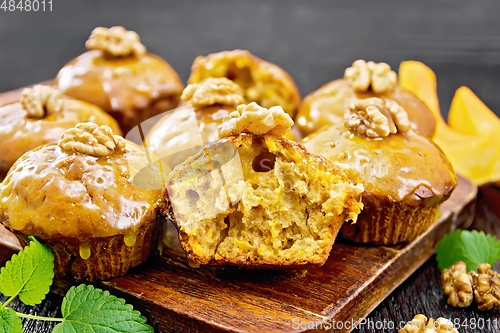 Image of Cupcake pumpkin with orange glaze and walnuts on wooden board