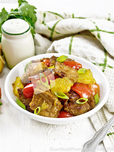 Image of Meat with oranges in bowl on wooden table