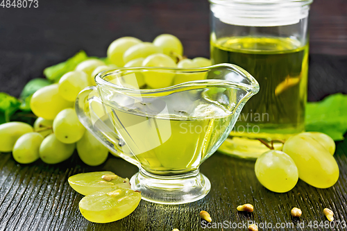 Image of Oil grape in gravy boat on dark board