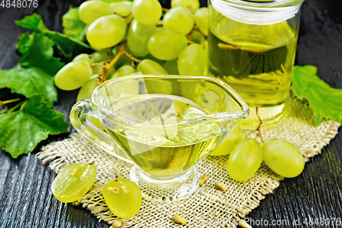 Image of Oil grape in gravy boat on wooden board