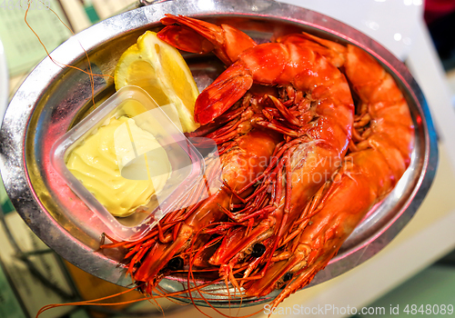 Image of Jumbo shrimps with lemon and sauce on metal plate 