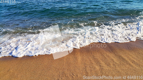 Image of Sea wave with white foam on the coastal sand