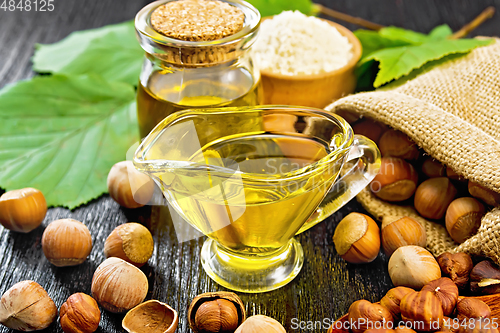 Image of Oil hazelnut in sauceboat on wooden board