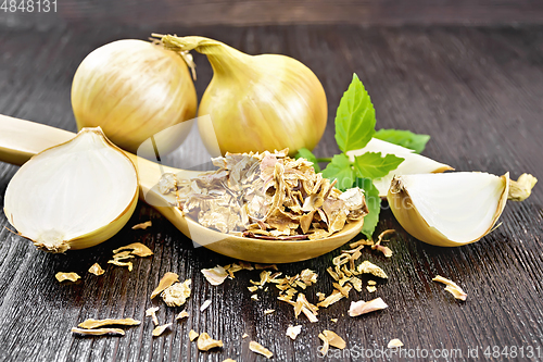 Image of Onion flakes in spoon on dark board