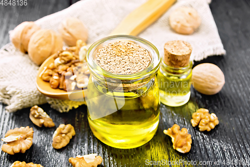 Image of Oil walnut in jar with spoon on dark board