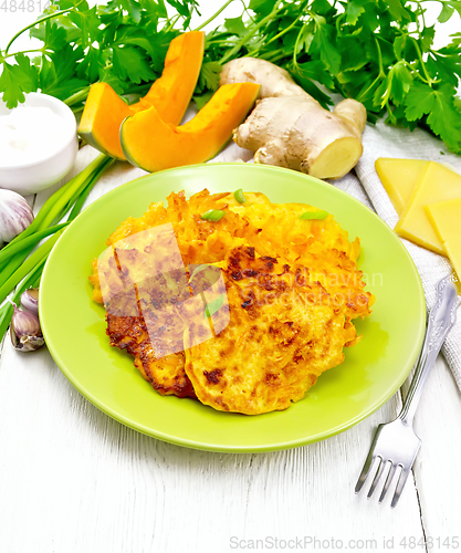 Image of Pancakes of pumpkin with cheese in green plate on white wooden b