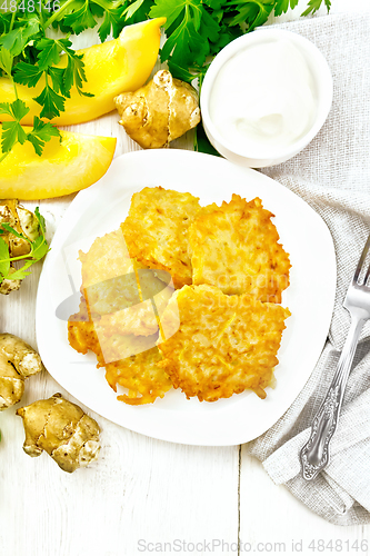 Image of Pancakes of pumpkin with Jerusalem artichoke in plate on board t