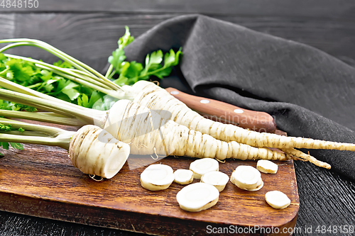 Image of Parsley root chopped with knife on black board