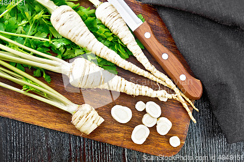 Image of Parsley root chopped with knife on dark board top