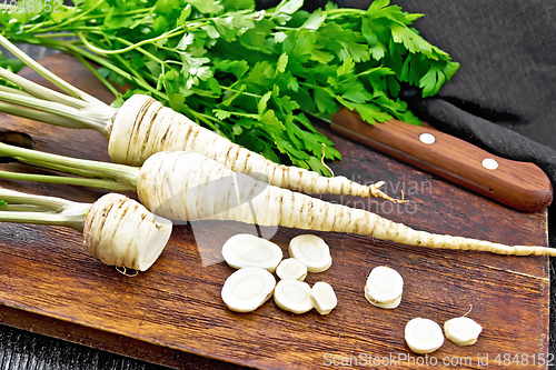 Image of Parsley root chopped with knife on dark board