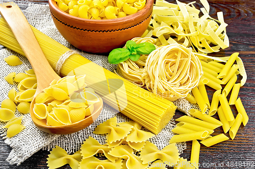 Image of Pasta different with basil on dark board