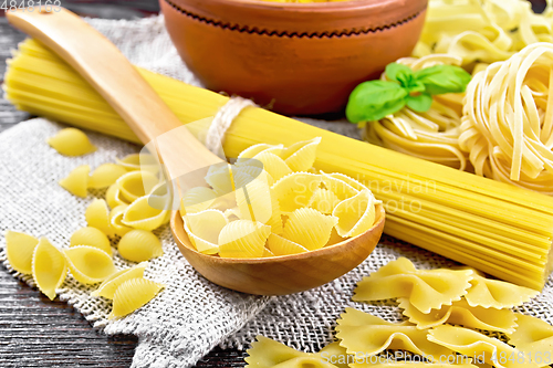 Image of Pasta different with basil on wooden board