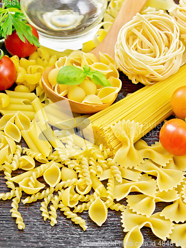 Image of Pasta different with oil and tomatoes on board