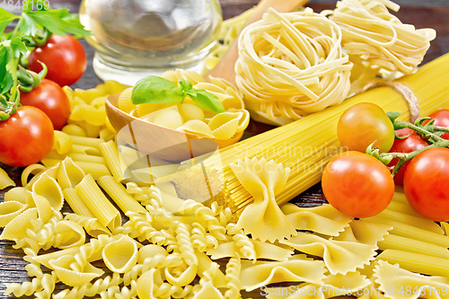 Image of Pasta different with oil and tomatoes on wooden board