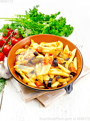 Image of Pasta penne with eggplant and tomatoes on wooden board