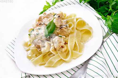 Image of Pasta with salmon in cream on wooden board