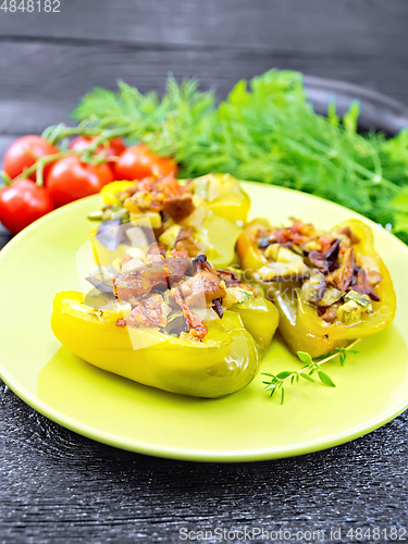 Image of Pepper stuffed with vegetables in green plate on black wooden bo