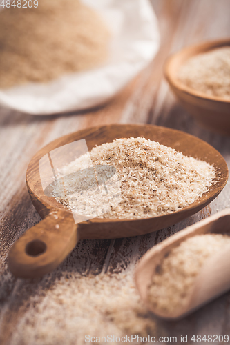 Image of Isabgol - heap of psyllium husk in wooden bowl on wooden table table