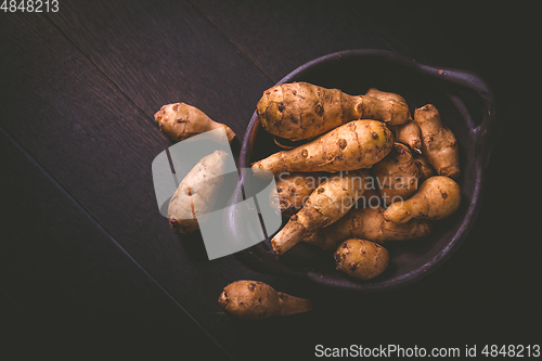 Image of Raw topinambour in bowl on wooden background