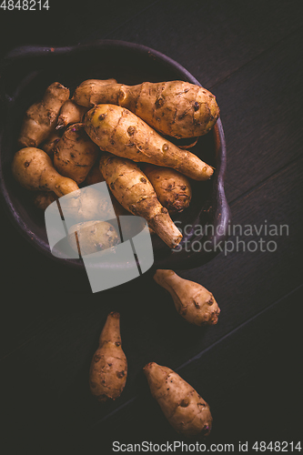 Image of Raw topinambour in bowl on wooden background