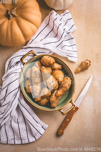 Image of Raw topinambour with pumpkins in bowl on kitchen table