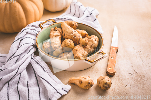 Image of Raw topinambour with pumpkins in bowl on kitchen table