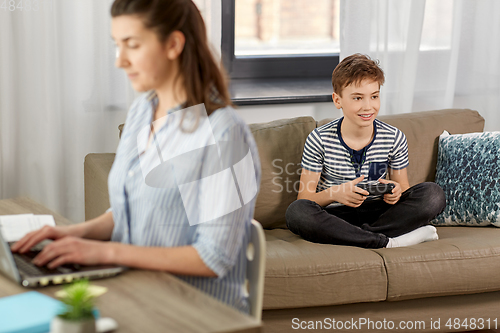 Image of boy with gamepad playing video game at home