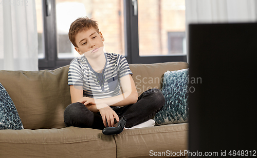 Image of sad boy with gamepad playing video game at home