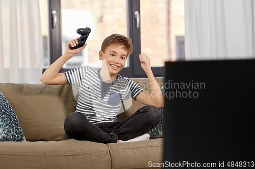 Image of happy boy with gamepad playing video game at home