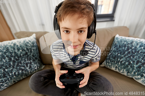 Image of boy with gamepad playing video game at home