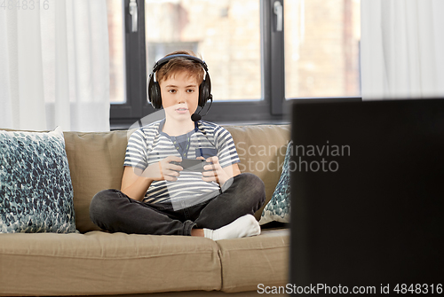 Image of boy with gamepad playing video game at home