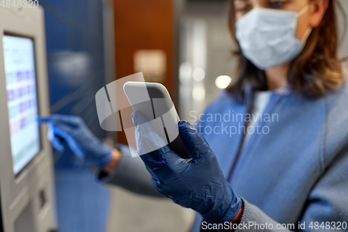 Image of woman in mask with smartphone at parcel machine