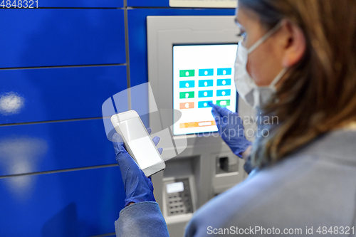 Image of woman in mask with smartphone at parcel machine