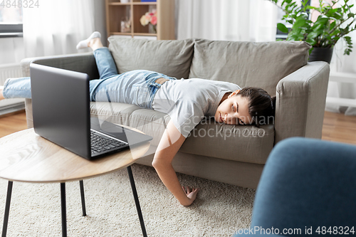 Image of bored woman with laptop lying on sofa at home